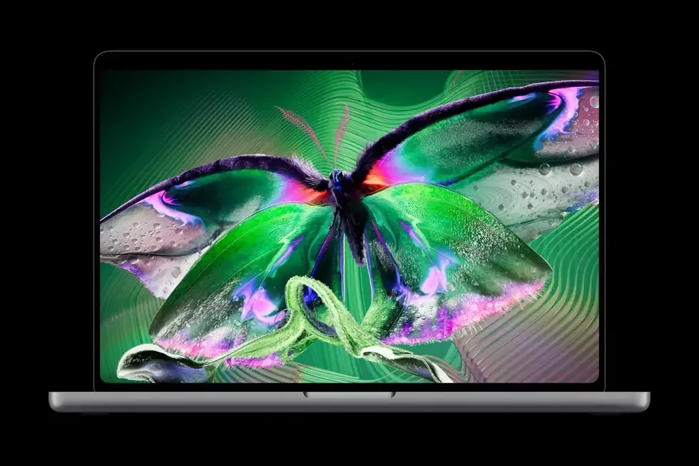 Otvoren Apple MacBook Pro sa šarenim leptirom na PROLED XDR OLED ekranu