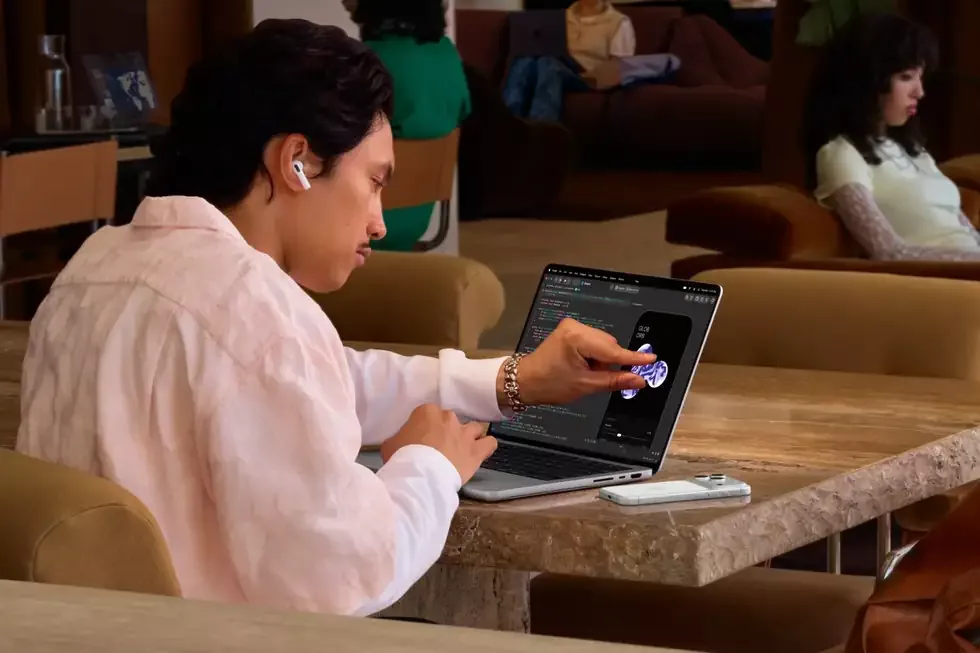 Korisnik sedi za stolom i dodiruje ekran otvorenog MacBooka Pro sa PROLED XDR panelom