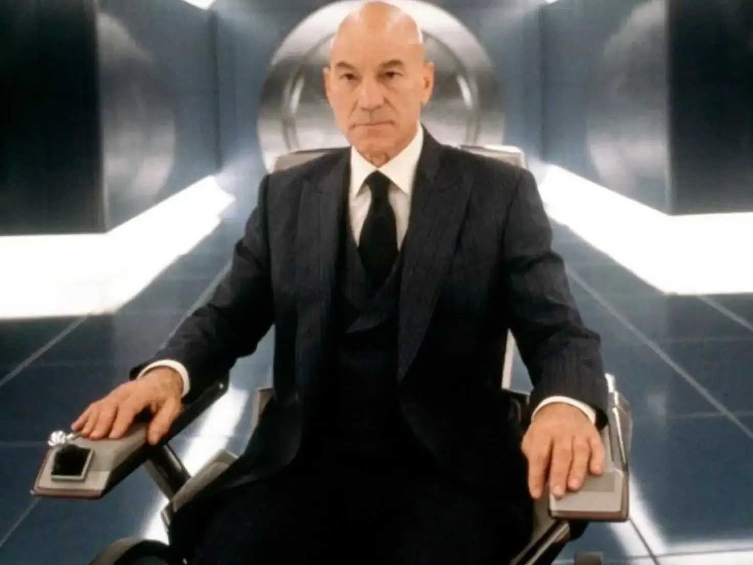 Patrick Stewart u ulozi Profesora Iksa, u tamnom odelu i kravati.